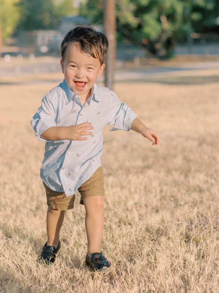 little boy running through field at White Rock Lake Dallas TX by Kate White Photography