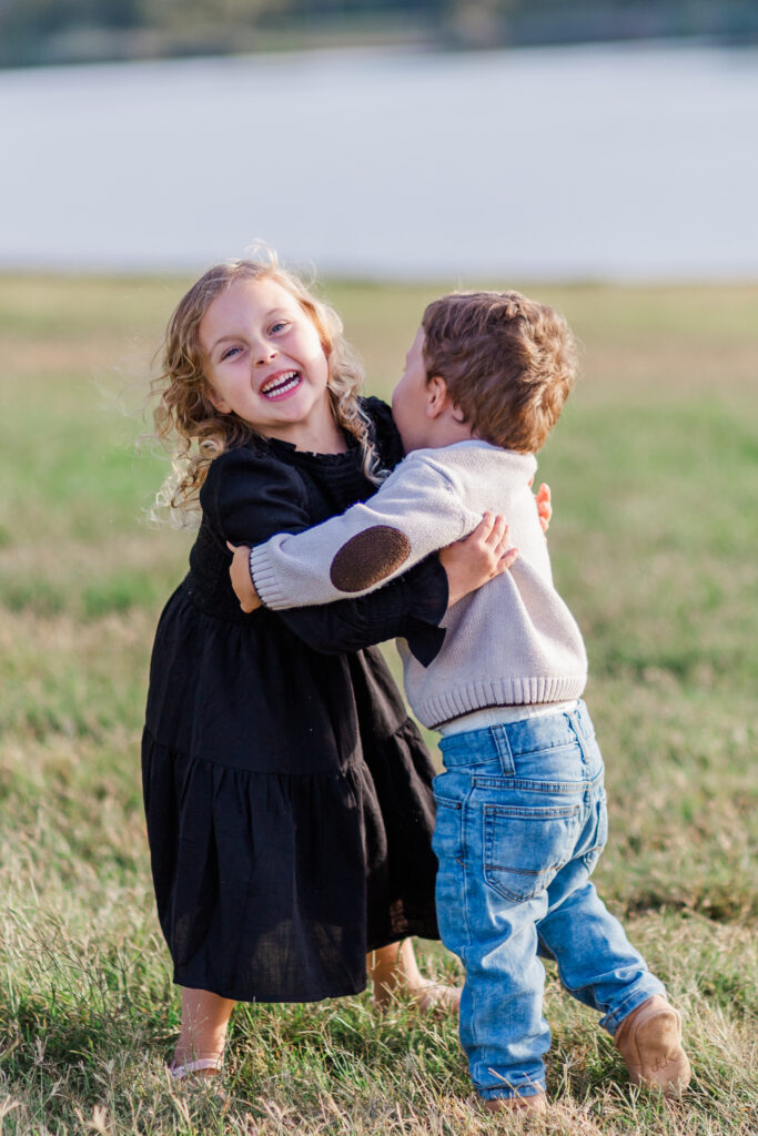 sister hugs brother at Mill Creek Reservoir Park in Canton TX with Kate White Photography