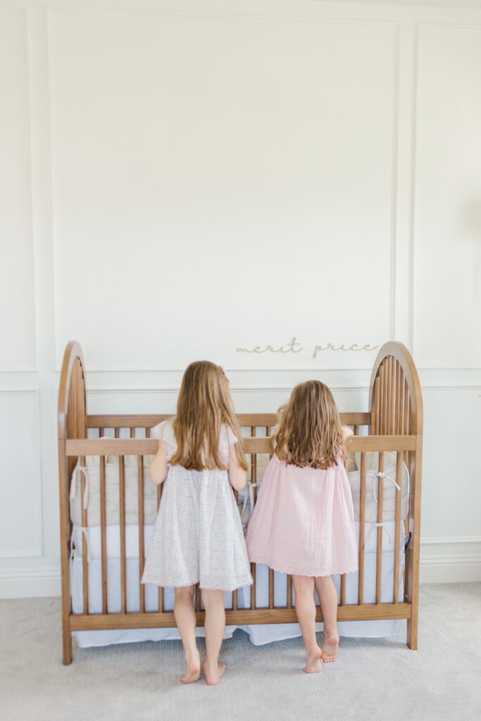 sisters peek into crib