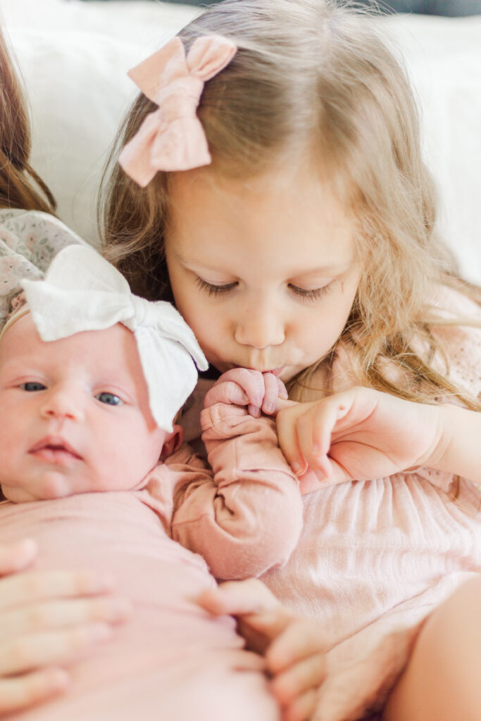 sister kisses babys hand