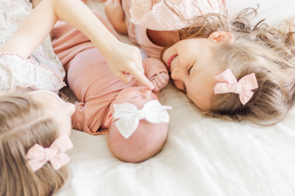 sisters snuggle baby girl