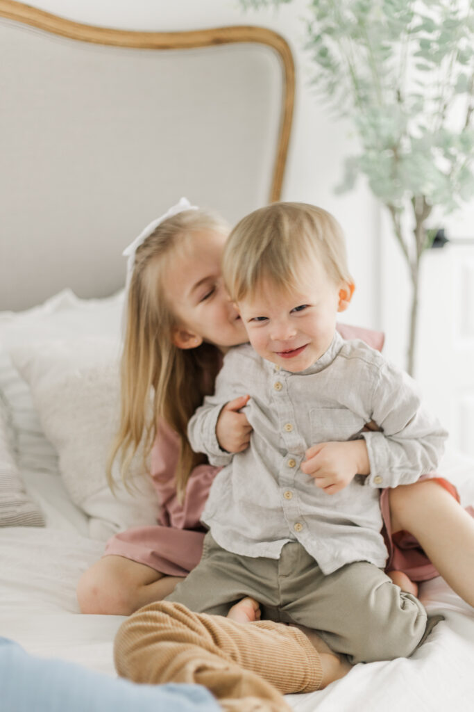 brother and sister playing on bed at Lemon Drop Studios in McKinney TX