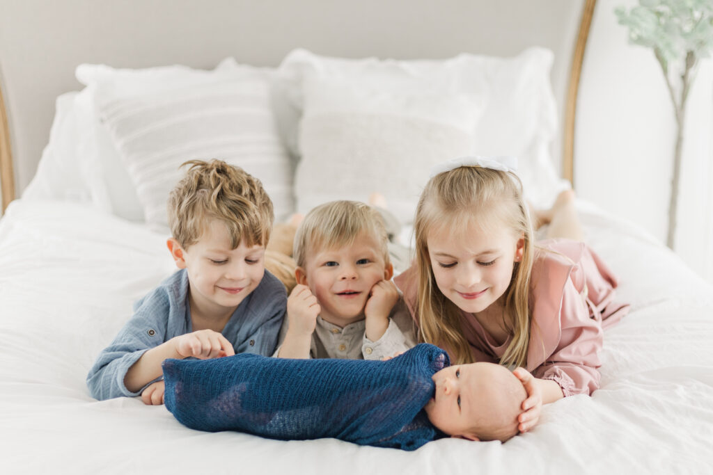 siblings with new baby on a bed at Lemon Drop Studios in McKinney TX