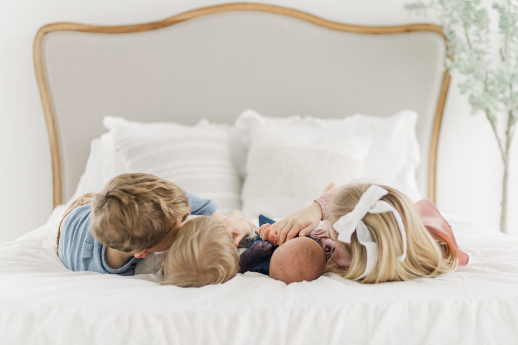 siblings with new baby on a bed at Lemon Drop Studios in McKinney TX