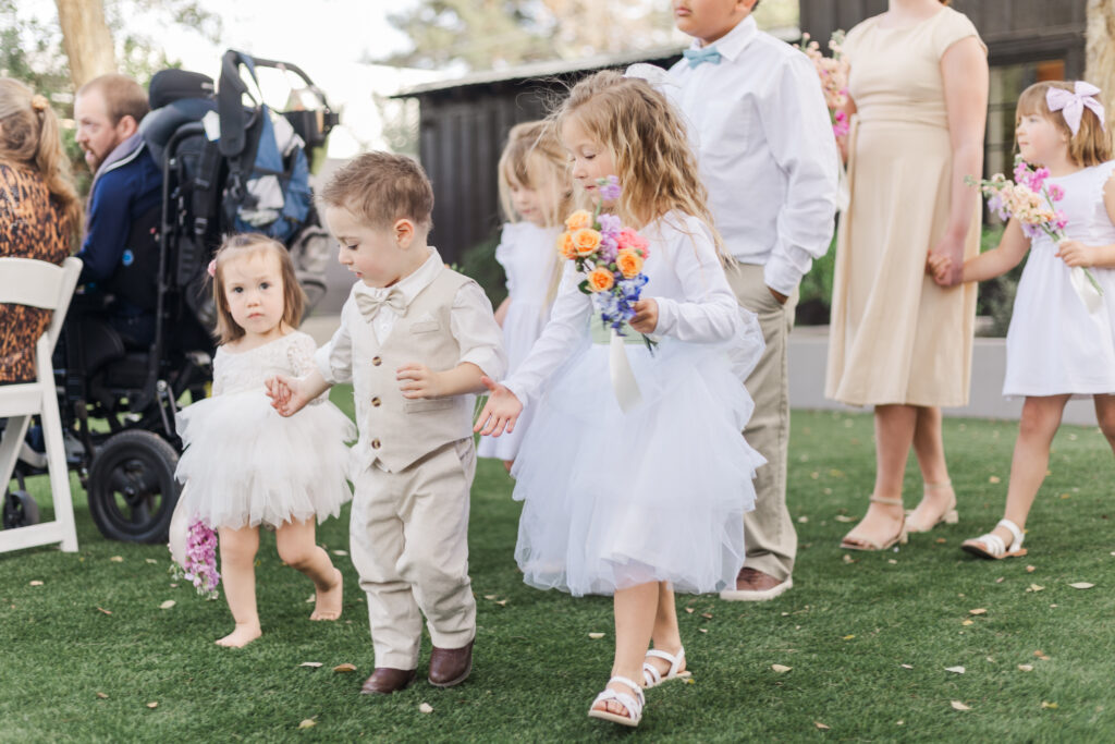 9 flower girls and ring bearers walk down the aisle hand in hand