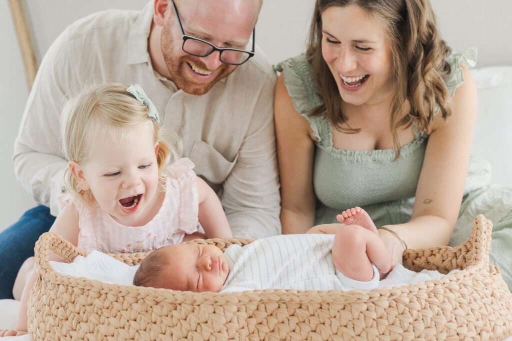 family smiling at laughing with newborn baby boy